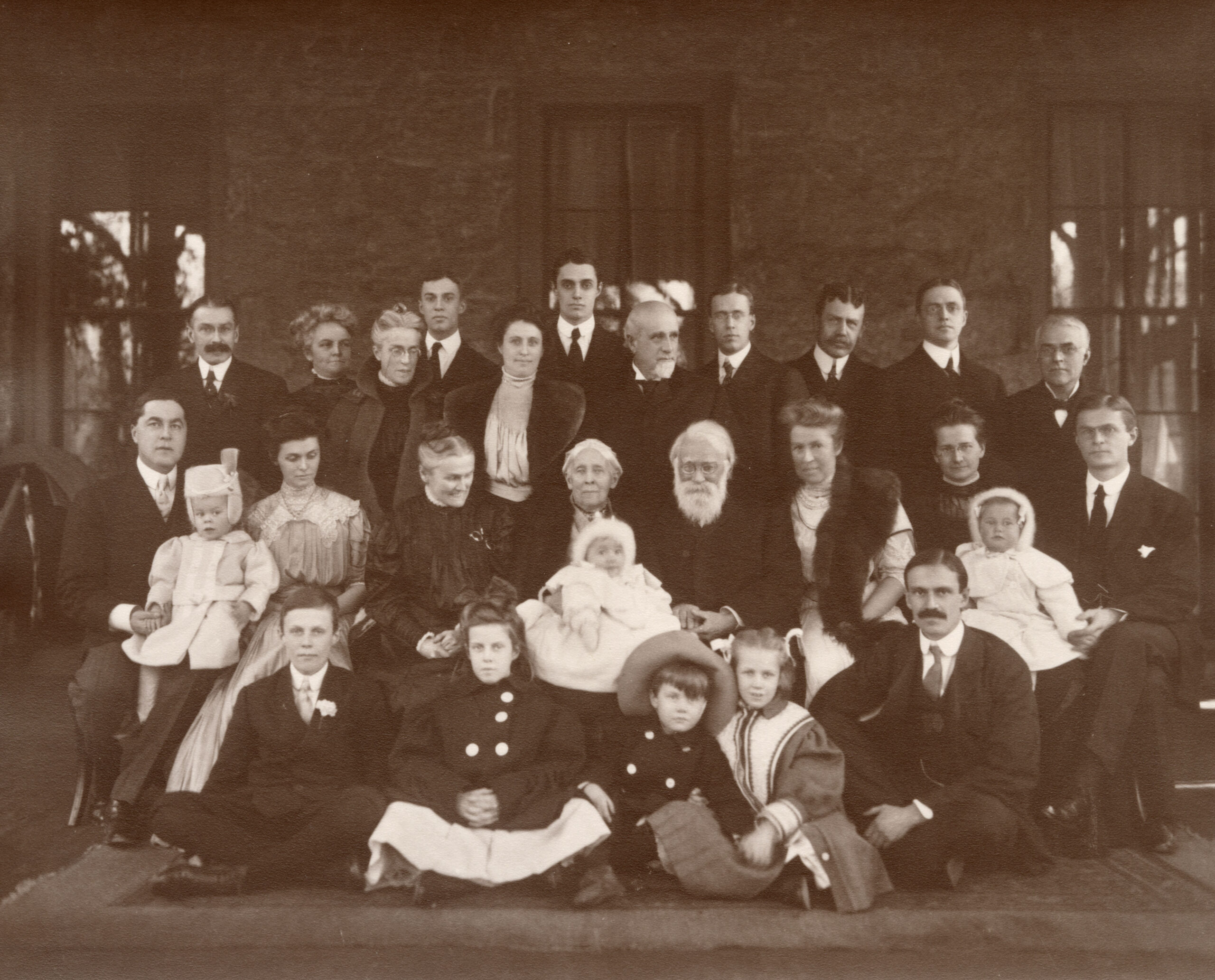 Black and white photograph of about 30 family members spanning several generations in front of a house. 
